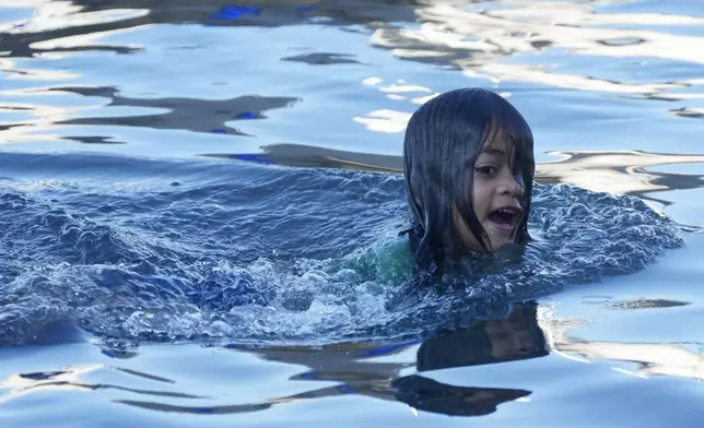 A young girl swims at the dock where fishing boats launch in the village of Siumu, Samoa, on Tuesday, Oct. 22, 2024. (AP Photo/Rick Rycroft)