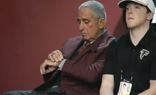 Atlanta Falcons owner Arthur Blank, left, looks at his watch during head coach Raheem Morris' press conference following their loss to the Seattle Seahawks in an NFL football game, Sunday, Oct. 20, 2024, in Atlanta. (AP Photo/ Mike Stewart)