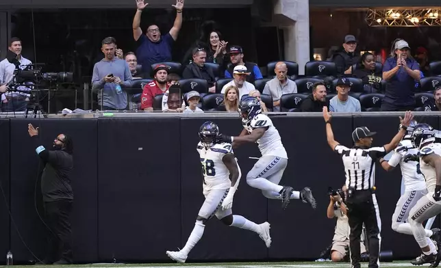 Seattle Seahawks linebacker Derick Hall (58) celebrates with Tyrel Dodson (0) after returning a fumble for a touchdown during the second half of an NFL football game against the Atlanta Falcons , Sunday, Oct. 20, 2024, in Atlanta. (AP Photo/Brynn Anderson)