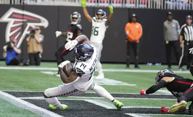 Seattle Seahawks wide receiver DK Metcalf (14) scors a touchdown as Atlanta Falcons safety Jessie Bates III (3) defends during the first half of an NFL football game, Sunday, Oct. 20, 2024, in Atlanta. (AP Photo/ Brynn Anderson)