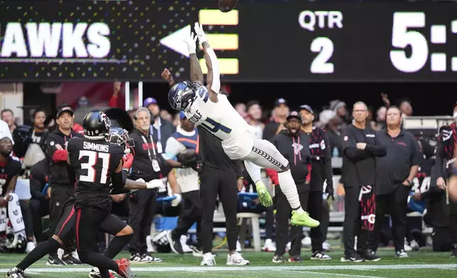 Seattle Seahawks wide receiver DK Metcalf (14) makes a catch as Atlanta Falcons safety Justin Simmons (31) defends during the first half of an NFL football game, Sunday, Oct. 20, 2024, in Atlanta. (AP Photo/ Brynn Anderson )