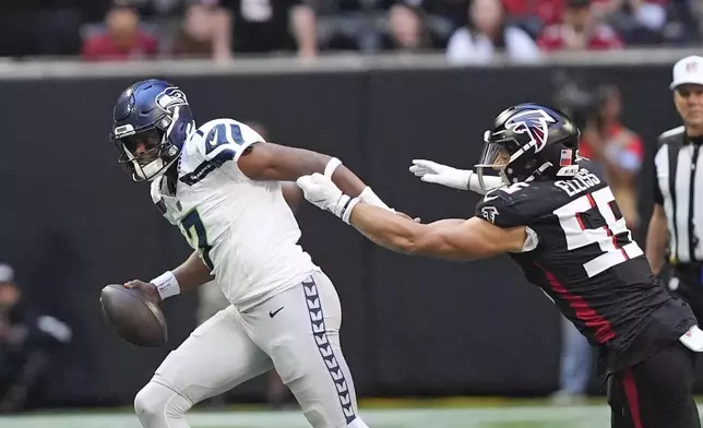 Seattle Seahawks quarterback Geno Smith (7) escapes from Atlanta Falcons linebacker Kaden Elliss (55) during the first half of an NFL football game, Sunday, Oct. 20, 2024, in Atlanta. (AP Photo/ Brynn Anderson )