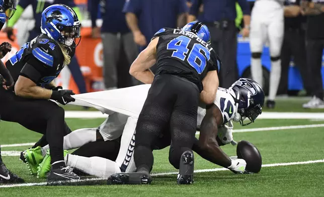 Detroit Lions linebacker Jack Campbell (46) hits Seattle Seahawks wide receiver DK Metcalf (14) and forces a fumble during the first half of an NFL football game, Monday, Sept. 30, 2024, in Detroit. (AP Photo/Jose Juarez)