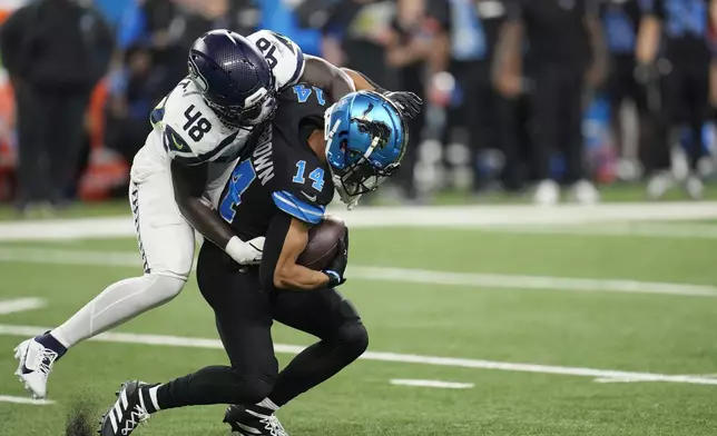 Detroit Lions wide receiver Amon-Ra St. Brown (14) is tackled by Seattle Seahawks linebacker Tyrice Knight (48) during the first half of an NFL football game, Monday, Sept. 30, 2024, in Detroit. (AP Photo/Paul Sancya)