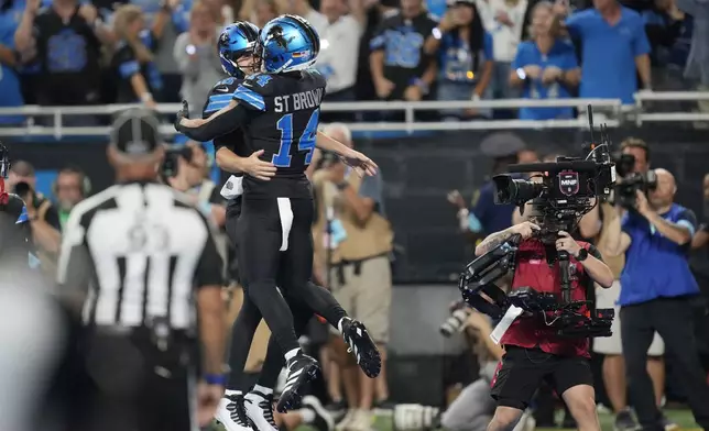 Detroit Lions quarterback Jared Goff, left, celebrates his rushing touchdown with teammate Amon-Ra St. Brown, who threw to Goff, during the second half of an NFL football game against the Seattle Seahawks, Monday, Sept. 30, 2024, in Detroit. (AP Photo/Paul Sancya)