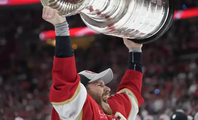 FILE - Florida Panthers left wing Matthew Tkachuk raises the Stanley Cup trophy after defeating the Edmonton Oilers, Monday, June 24, 2024, in Sunrise, Fla. (AP Photo/Wilfredo Lee, File)