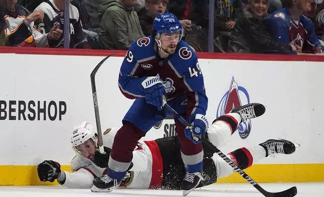 Colorado Avalanche defenseman Samuel Girard, front, collects the puck as Ottawa Senators right wing Michael Amadio falls in pursuit in the second period of an NHL hockey game Sunday, Oct. 27, 2024, in Denver. (AP Photo/David Zalubowski)