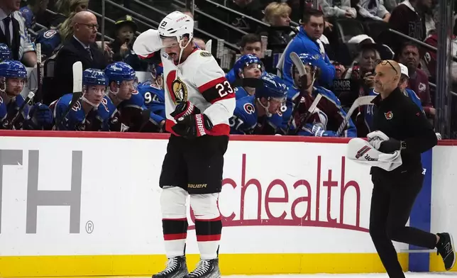 A trainer, right, follows Ottawa Senators defenseman Travis Hamonic, left, who skates off the ice after being injured in the second period of an NHL hockey game against the Colorado Avalanche, Sunday, Oct. 27, 2024, in Denver. (AP Photo/David Zalubowski)