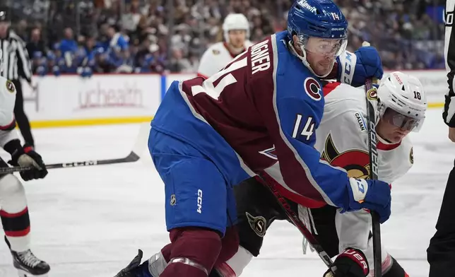 Colorado Avalanche right wing Chris Wagner (14) uses his stick to check Ottawa Senators center Tim Stützle (18) as they pursue the puck in the second period of an NHL hockey game Sunday, Oct. 27, 2024, in Denver. (AP Photo/David Zalubowski)