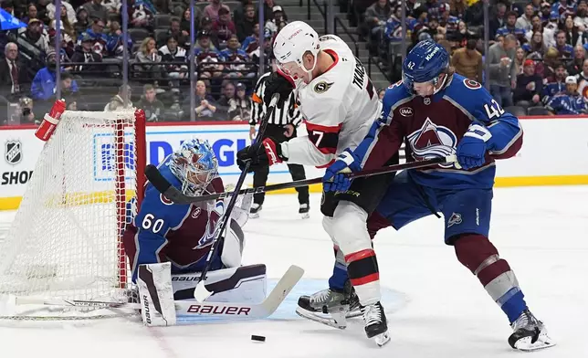 Ottawa Senators left wing Brady Tkachuk, center, struggles to shoot against Colorado Avalanche goaltender Justus Annunen, left, as Avalanche defenseman Josh Manson, right, battles for position in the second period of an NHL hockey game Sunday, Oct. 27, 2024, in Denver. (AP Photo/David Zalubowski)