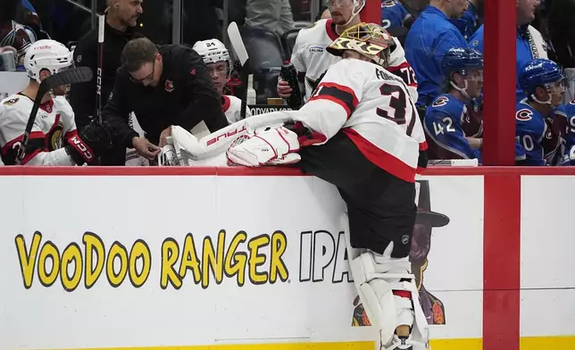 An equipment manager, third from left, tries to repair a skate of Ottawa Senators goaltender Anton Forsberg, front, in the second period of an NHL hockey game against the Colorado Avalanche, Sunday, Oct. 27, 2024, in Denver. (AP Photo/David Zalubowski)