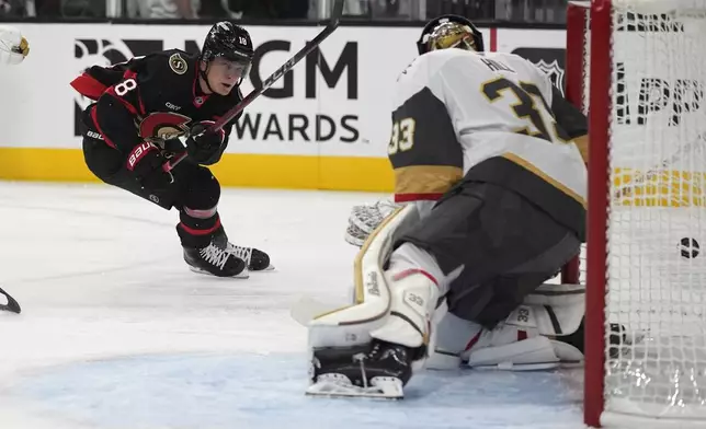 Ottawa Senators center Tim Stützle (18) attempts a shot on Vegas Golden Knights goaltender Adin Hill (33) during the first period of an NHL hockey game Friday, Oct. 25, 2024, in Las Vegas. (AP Photo/John Locher)