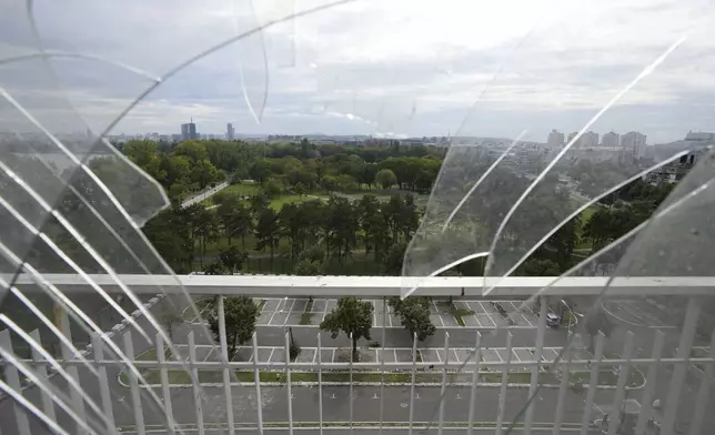 A general view of Belgrade is partially seen through the broken window from Hotel Yugoslavia, once a symbol of progress in the former socialist state of Yugoslavia that broke apart in the 1990s and a favorite gathering place for local residents as well as world leaders, in Belgrade, Serbia, Thursday, Oct. 3, 2024. (AP Photo/Darko Vojinovic)