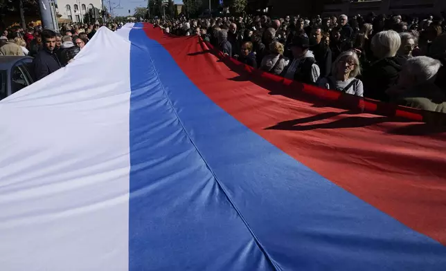 People hold a giant Serbian flag during the ceremony on the occasion of the 80th anniversary of the liberation of Belgrade from Nazi occupation in WWII by Soviet and local communist fighters, in Belgrade, Serbia, Sunday, Oct. 20, 2024. (AP Photo/Darko Vojinovic)