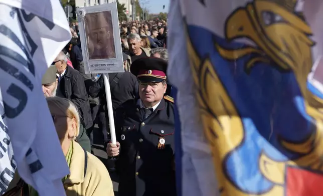 People hold pictures of relatives killed in WWII during a ceremony on the occasion of the 80th anniversary of the liberation of Belgrade from Nazi occupation in WWII by Soviet and local communist fighters, in Belgrade, Serbia, Sunday, Oct. 20, 2024. (AP Photo/Darko Vojinovic)