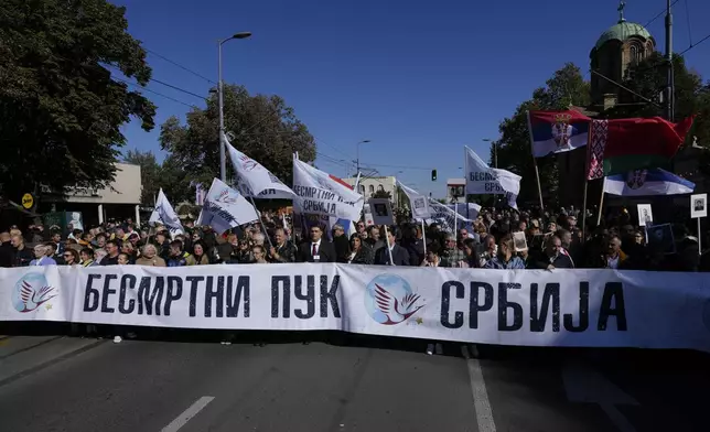 People march with portraits of relatives who were killed in World War II behind a banner that reads: "Immortal Regiment Serbia", during the ceremony on the occasion of the 80th anniversary of the liberation of Belgrade from Nazi occupation in WWII by Soviet and local communist fighters, in Belgrade, Serbia, Sunday, Oct. 20, 2024. (AP Photo/Darko Vojinovic)