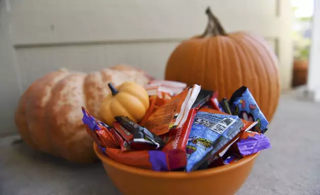 Halloween candy and pumpkins sit outside of a home Friday, Oct. 11, 2024, in St. Joseph, Mo. (AP Photo/Nick Ingram)