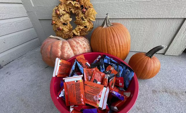 Halloween candy and pumpkins sit outside of a home Friday, Oct. 11, 2024, in St. Joseph, Mo. (AP Photo/Nick Ingram)