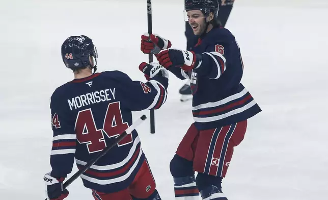 Winnipeg Jets' Josh Morrissey (44) and Colin Miller (6) celebrate after Morrissey's goal against the San Jose Sharks during first-period NHL hockey game action in Winnipeg, Manitoba, Friday, Oct. 18, 2024. (John Woods/The Canadian Press via AP)