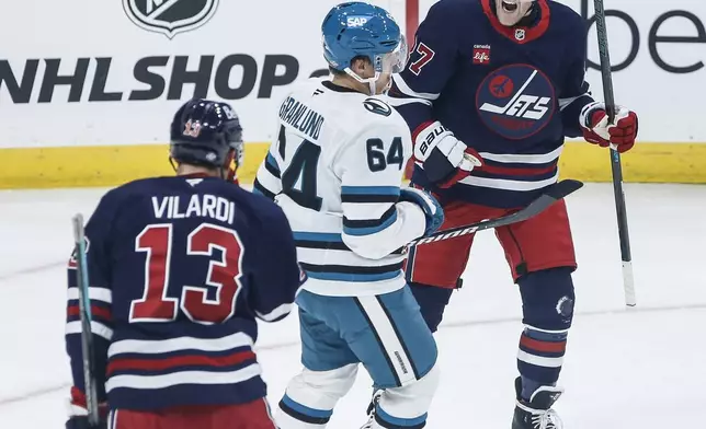 Winnipeg Jets' Gabriel Vilardi (13) and Nikolaj Ehlers (27) celebrate after Ehlers' goal as San Jose Sharks' Mikael Granlund (64) skates past during first-period NHL hockey game action in Winnipeg, Manitoba, Friday, Oct. 18, 2024. (John Woods/The Canadian Press via AP)