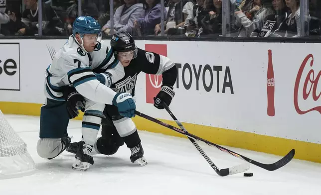 San Jose Sharks center Nico Sturm (7) and Los Angeles Kings defenseman Jordan Spence (21) vie for the puck during the third period of an NHL hockey game Thursday, Oct. 24, 2024, in Los Angeles. (AP Photo/William Liang)