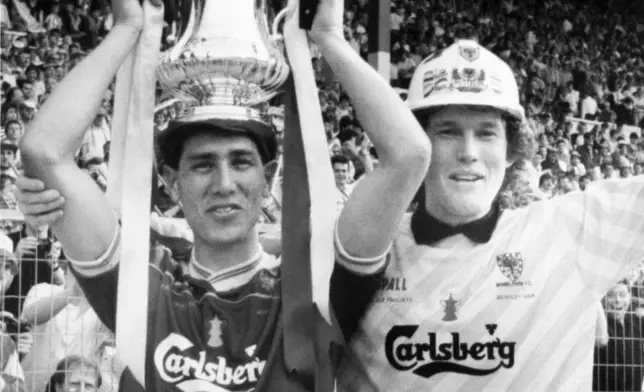 FILE - Wimbledon FC soccer player Lawrie Sanchez, holds the FA Cup as captain/goalkeeper David Beasant, acknowledges the cheers of their fans after their team beat Liverpool FC 1-0 in the FA Cup Final at Wembley Stadium in London, United Kingdom, on Saturday, May 14, 1988. (AP Photo/Bob Dear, File)