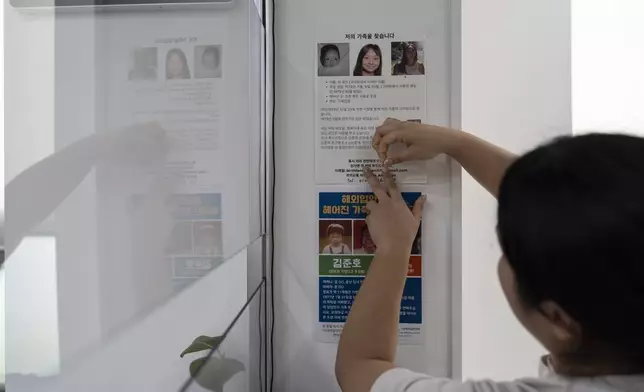 A city employee posts a flyer with photos of adoptee Maja Andersen from various ages in life and details about her birth search on the wall of a police station in Incheon, South Korea, Monday, May 20, 2024, above another left by an adoptee also searching for his roots. Andersen was adopted to a family in Denmark when she was an infant. (AP Photo/Jae C. Hong)