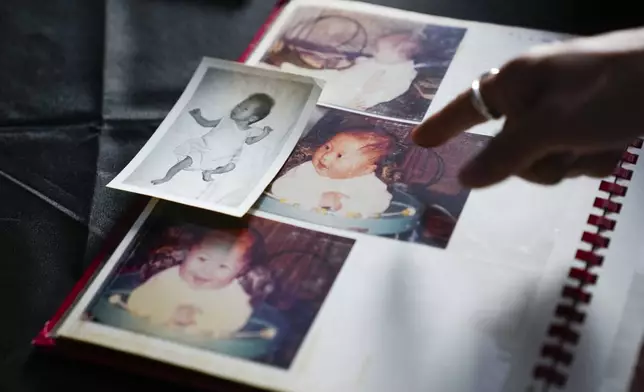 Rebecca Kimmel points to color photos of herself after being adopted, next to a photo of a girl used in her adoption file that she believes is a different baby, Saturday, July 1, 2023, at her art studio in Seattle. AP Photo/Lindsey Wasson)