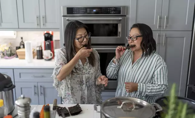 Dee Iraca, left, and Becca Webster, twins who were adopted out of South Korea to a family in the United States, try Korean-style roasted seaweed Iraca made at her home in Davidson, N.C., Saturday, April 6, 2024. The sisters always considered themselves very different which prompted them to take a DNA test in the first place; they wanted to confirm for themselves that they are biological sisters. The test result not only confirmed thy are twins, but eventually led them to their birth father. (AP Photo/David Goldman)