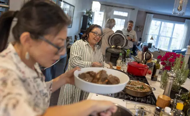 Dee Iraca, left, and her twin sister, Becca Webster, who both were adopted out of South Korea to a family in the United States, host guests at a dinner party Saturday, April 6, 2024, at Iraca's home in Davidson, N.C. Webster, a nanny with a son in college, is whimsical, chatty and easygoing. Iraca, who works as a chef and dietitian, is meticulous, serious and always on the go. (AP Photo/David Goldman)