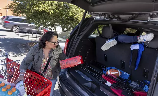 Becca Webster, who was adopted as a baby out of South Korea to a family in the United States, loads up the back of a van with groceries while nannying for a family Friday, April 5, 2024, in Davidson, N.C. She and her sister ended up happy in America, but resent that they learned of their identity from a stranger, and that they were too late to meet their mother. (AP Photo/David Goldman)