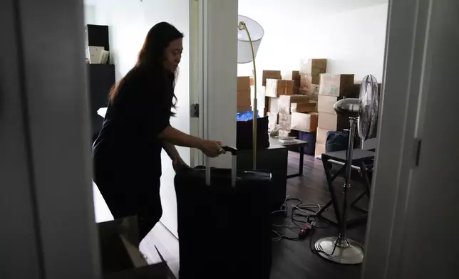 Adoptee Rebecca Kimmel wheels her luggage through her apartment as she prepares for her flight to South Korea to investigate her identity story, Sunday, July 2, 2023, in Seattle. In 2017, Kimmel went to a three-day event in San Francisco with hundreds of Korean adoptees and the new ideas and friendships prompted a deep sense of urgency. (AP Photo/Lindsey Wasson)