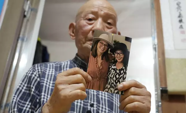 Park Jong-kyun holds a photo showing his twin daughters, Dee Iraca, left, and Becca Webster, at his house on Jeju Island, South Korea, Wednesday, Feb. 21, 2024. His twins were born at a time when he and his late wife were struggling financially to raise three sons. His wife needed an emergency C-section, which the couple couldn't afford. The hospital persuaded them to give away the twins to relieve the financial burden and toll on his wife's health, Park says. (AP Photo/Ahn Young-joon)