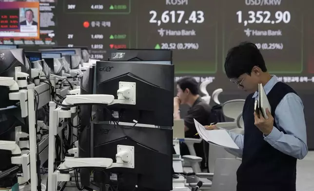 A currency trader reads documents at the foreign exchange dealing room of the KEB Hana Bank headquarters in Seoul, South Korea, Monday, Oct. 14, 2024. (AP Photo/Ahn Young-joon)