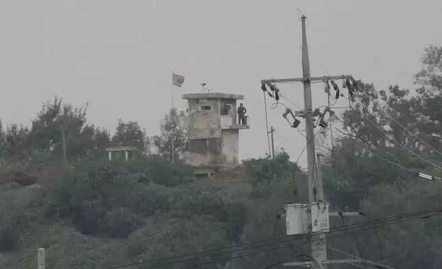 A North Korean soldier stands guard at the North's military guard post as a North Korean flag flutters in the wind, as seen from Paju, South Korea, near the border with North Korea, Monday, Oct. 14, 2024. (AP Photo/Ahn Young-joon)