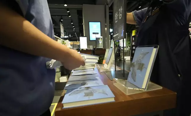 Workers display South Korean author Han Kang's books at a special section at a bookstore in Goyang, South Korea, Thursday, Oct. 10, 2024. The letters read "Han Kang, Awarded the Nobel Prize in literature." (AP Photo/Lee Jin-man)