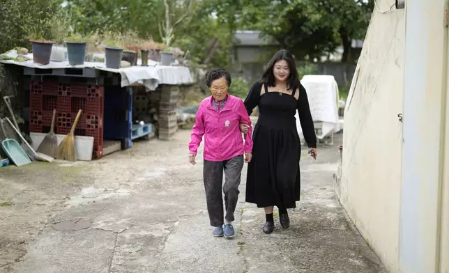 82-year-old Park Jeom-sun walks with her granddaughter Kang Hye-eun outside their old house in Chilgok, South Korea, Thursday, Oct. 3, 2024. (AP Photo/Lee Jin-man)