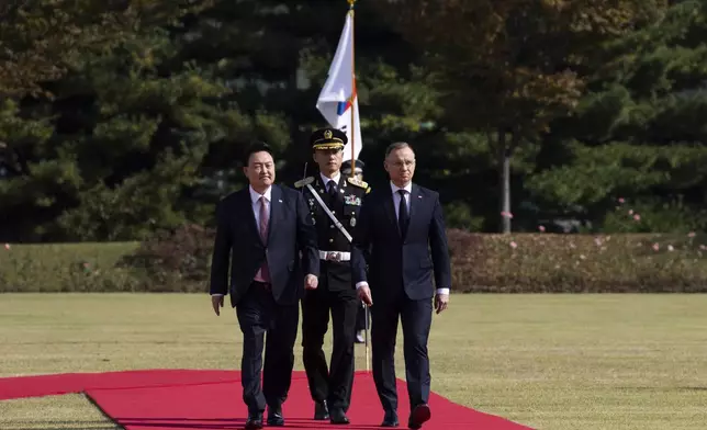 South Korean President Yoon Suk Yeol, left, and Poland's President Andrzej Duda, right, walk with honor guards during a welcoming ceremony at the Presidential Office in Seoul, South Korea, Thursday, Oct. 24, 2024. (Jeon Heon-Kyun/Pool Photo via AP)