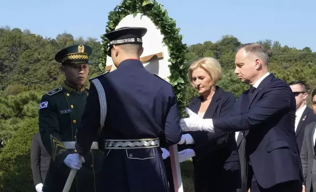 Polish President Andrzej Duda, right, and his wife Agata Kornhauser-Duda offer a wreath at the National Cemetery in Seoul, South Korea, Thursday, Oct. 24, 2024. (AP Photo/Ahn Young-joon)