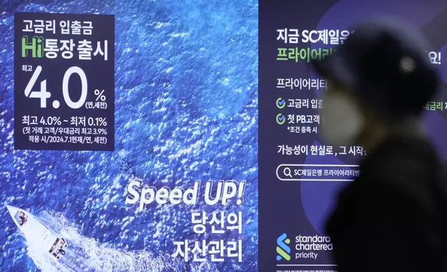 A woman passes by an advertisement for deposit interest rates at a bank in Seoul, South Korea, Friday, Oct. 11, 2024. (AP Photo/Ahn Young-joon)