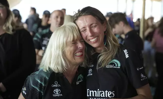 Emma Outteridge, right, wife of Nathan Outteridge, a crew member of the Emirates Team New Zealand, reacts as their team won the Louis Vuitton 37th America's Cup in Barcelona, Spain, Saturday, Oct. 19, 2024. (AP Photo/Emilio Morenatti)