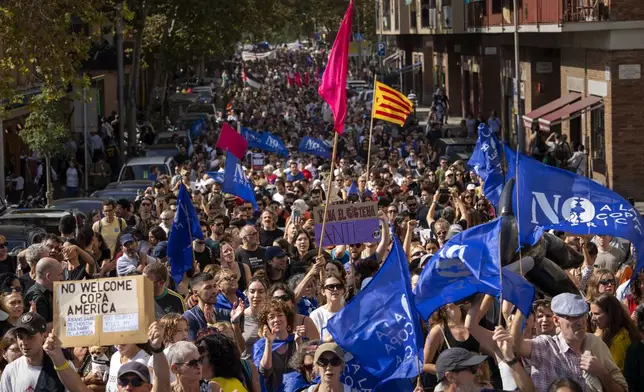 Demonstrators march shouting slogans against the holding of the America's Cup sailing competition, during a protest demanding the right to housing, in Barcelona, Spain, Sunday, Oct. 13, 2024. (AP Photo/Emilio Morenatti)