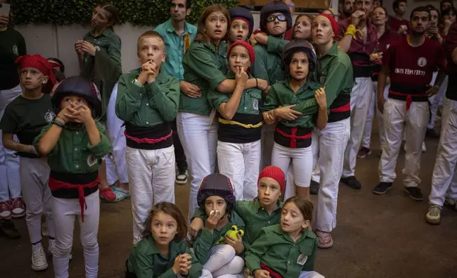 Assistants look as members of "Castellers Jove de Barcelona" form a "Castell" or human tower, during the 29th Human Tower Competition in Tarragona, Spain, Saturday, Oct. 5, 2024. (AP Photo/Emilio Morenatti)