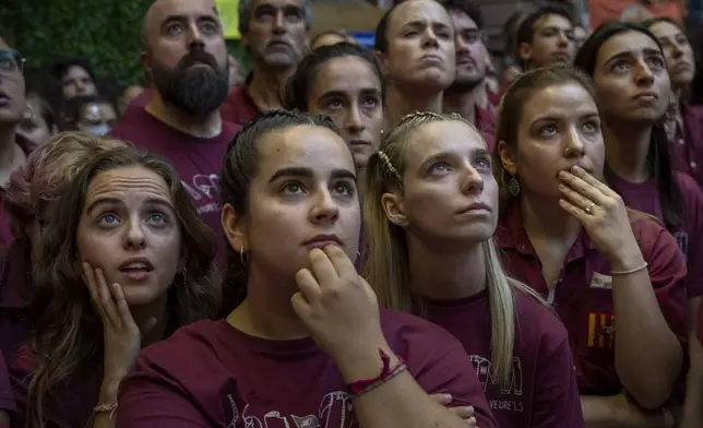 Assistants look as members of a "Castellers" form a human tower, during the 29th Human Tower Competition in Tarragona, Spain, Saturday, Oct. 5, 2024. (AP Photo/Emilio Morenatti)