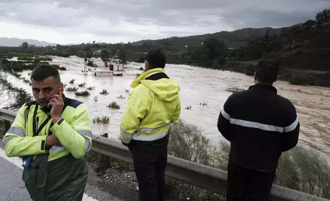 People look at the rising river, after floods preceded by heavy rains caused the river to overflow its banks in the town of Alora, Malaga, Spain, Tuesday, Oct. 29, 2024. (AP Photo/Gregorio Marrero)