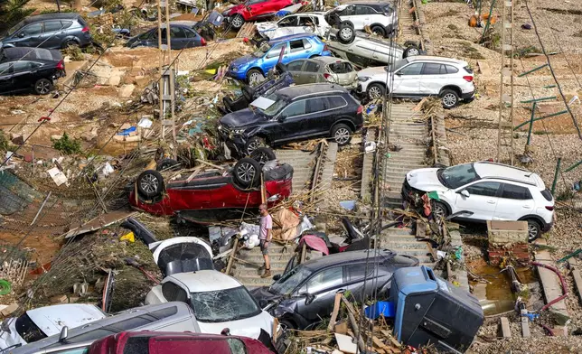 A man stands among flooded cars piled up in Valencia, Spain, Thursday, Oct. 31, 2024. (AP Photo/Manu Fernandez)