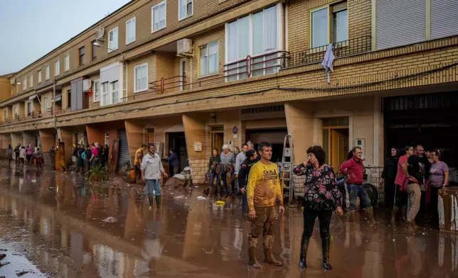 People stand in front of their houses affected by floods in Utiel, Spain, Wednesday, Oct. 30, 2024. (AP Photo/Manu Fernandez)