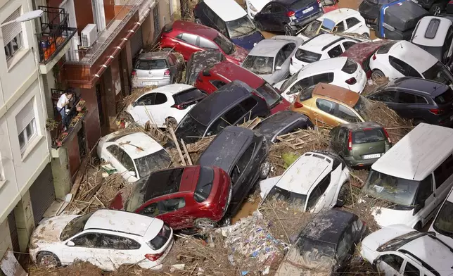 Residents look at cars piled up after being swept away by floods in Valencia, Spain, Wednesday, Oct. 30, 2024. (AP Photo/Alberto Saiz)