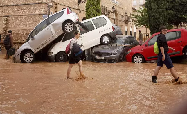 Residents walk through flooded streets in Valencia, Spain, Wednesday, Oct. 30, 2024. (AP Photo/Alberto Saiz)