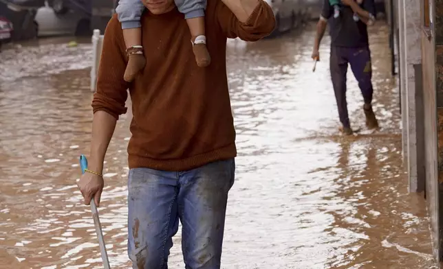 People walk through flooded streets in Valencia, Spain, Wednesday, Oct. 30, 2024. (AP Photo/Alberto Saiz)